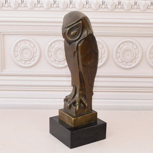 May include: A bronze sculpture of an owl with a geometric design. The owl is perched on a black base.