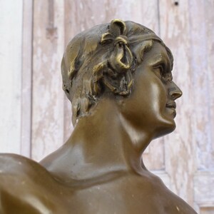 May include: Bronze sculpture of a person's bust, the person is facing to the right, with a detailed head and neck, and a smooth, polished surface.