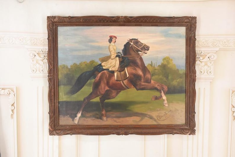 Pu&ograve; includere: Un dipinto ad olio antico in una cornice di legno scuro raffigura una persona che cavalca un cavallo marrone. Il cavaliere indossa un cappotto giallo e un cappello rosso. Il cavallo si impenna in un campo erboso con alberi sullo sfondo.
