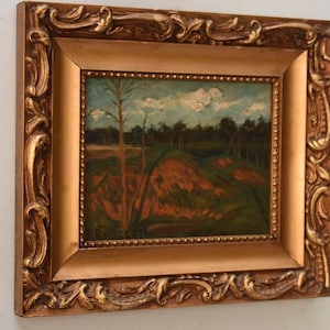 Könnte beinhalten: Ölgemälde einer Landschaft, gerahmt in einem goldenen, verzierten Rahmen. Das Gemälde zeigt einen Weg durch ein Feld mit Bäumen und einem bewölkten Himmel. Der Rahmen hat ein detailliertes, dekoratives Design.