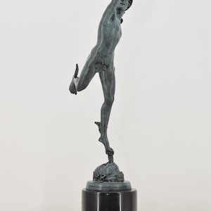 May include: A bronze statue of a male figure in a dynamic pose, with one arm raised and the other leg extended. The statue is mounted on a black marble base, showcasing classical art.