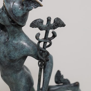 May include: A bronze statue of a mythological figure, possibly Hermes or Mercury, with a winged helmet and holding a staff with intertwined snakes. The statue has a verdigris patina, suggesting age or exposure to the elements. The figure is in a dynamic pose.