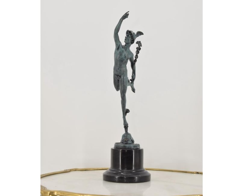 May include: A bronze statue of a male figure in a dynamic pose, with one arm raised and the other holding a staff. The statue is mounted on a black rectangular base. The figure has a winged helmet and is likely a depiction of a mythological character.