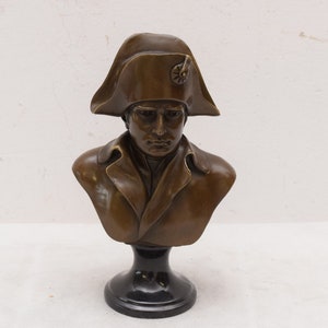 May include: Bronze bust sculpture of Napoleon Bonaparte wearing a bicorne hat on a black pedestal.
