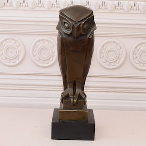 May include: A bronze sculpture of an owl with a geometric design. The owl is standing on a square base with a black marble base.