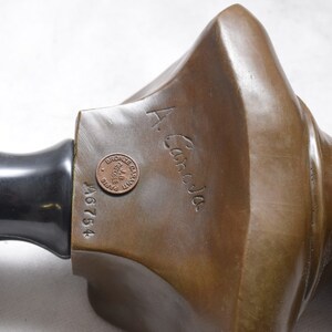 May include: Bronze sculpture bust with a black marble base. The bust is signed "A. Caroja" and has a bronze stamp with the inscription "Bronze d'Art Garantie Paris".