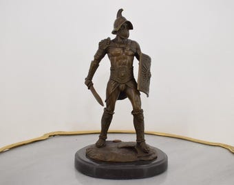 Escultura de caballero de bronce firmada: figura con armadura medieval sobre base de mármol.