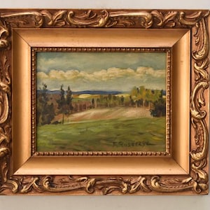 Könnte beinhalten: Ölgemälde einer Landschaftsszene, gerahmt in einem goldenen, verzierten Rahmen. Das Gemälde zeigt ein grünes Feld, Bäume und einen blauen Himmel mit Wolken. Die Signatur des Künstlers ist unten rechts sichtbar.