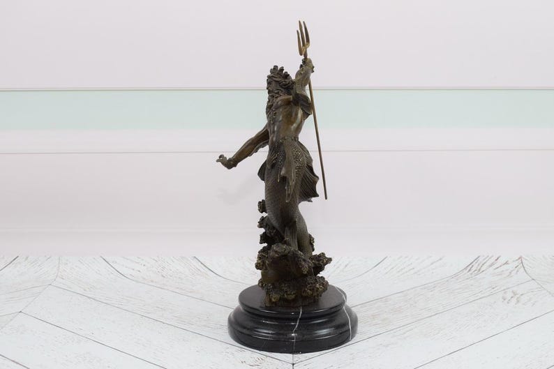 Puede incluir: Estatua de bronce de una figura m&iacute;tica, posiblemente Neptuno, sosteniendo un tridente. La figura est&aacute; posada con un brazo extendido y se alza sobre una base texturizada. La estatua tiene una p&aacute;tina marr&oacute;n oscuro y est&aacute; montada sobre una base de m&aacute;rmol negro.