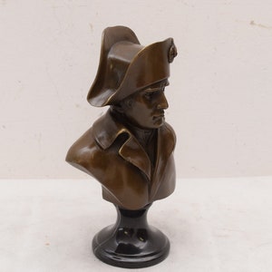 May include: Bronze bust sculpture of a man wearing a bicorne hat on a black marble base.