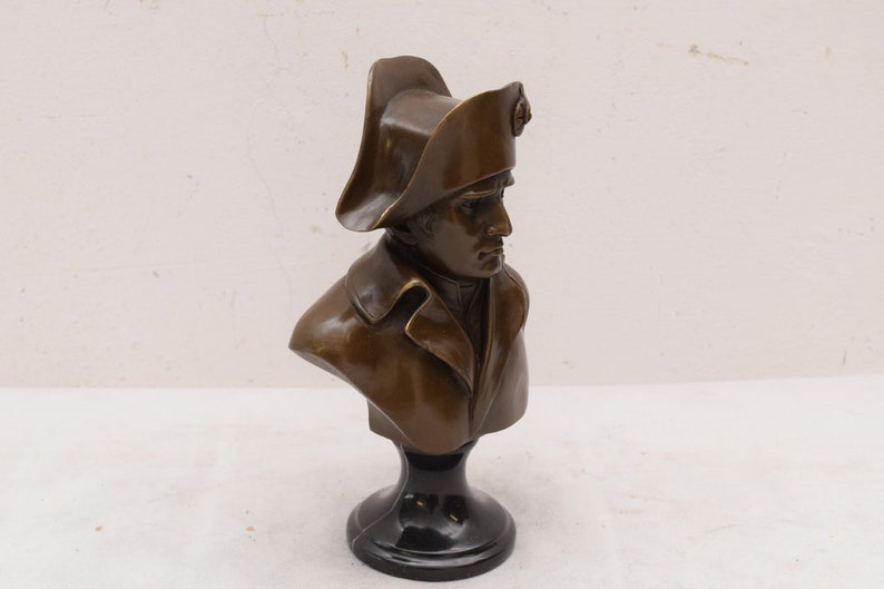 May include: Bronze bust sculpture of a man wearing a bicorne hat on a black marble base.