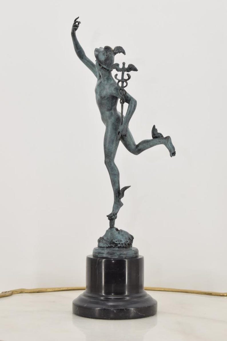 May include: A bronze statue of a figure in motion, possibly Mercury, with a winged helmet and staff. The statue is mounted on a black marble base. The figure is depicted with one arm raised and one leg extended, suggesting movement.
