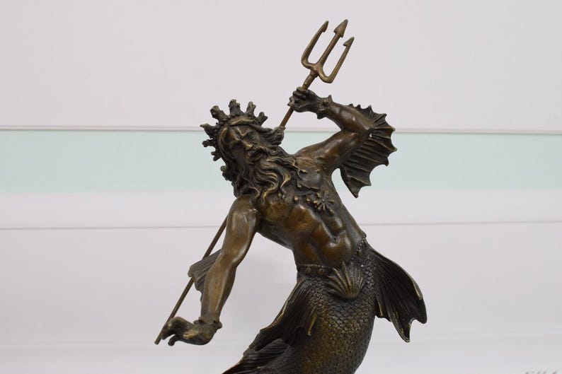 Puede incluir: Una escultura de bronce de una criatura marina m&iacute;tica, posiblemente Poseid&oacute;n o Neptuno, sosteniendo un tridente. La figura tiene una corona, pelo largo y una cola de pez. La escultura es detallada y parece antigua.