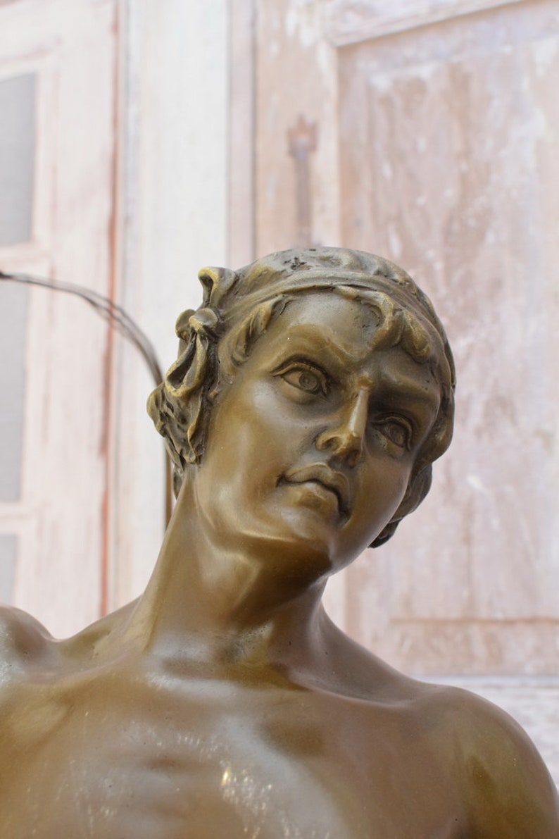 May include: Bronze sculpture of a man's head and shoulders. The man is looking up and to the right. His face is detailed and expressive. The sculpture is a classic example of Renaissance art.