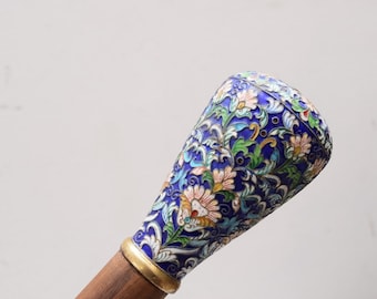 May include: A decorative walking stick with a blue, green, white, and gold enamel handle featuring a floral design.