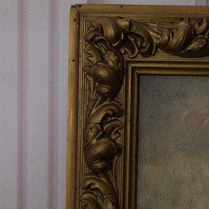 K&ouml;nnte beinhalten: Ein verzierter Bilderrahmen in Gold mit einem detaillierten, geschnitzten Design. Der Rahmen ist aus Holz und hat eine leicht abgenutzte Oberfl&auml;che.
