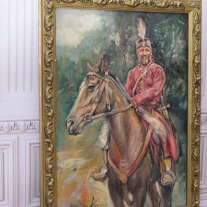 K&ouml;nnte beinhalten: Ein gerahmtes &Ouml;lgem&auml;lde eines Mannes auf einem Pferd. Der Mann tr&auml;gt eine rot-goldene Uniform und einen Federhut. Das Pferd ist braun und hat ein wei&szlig;es Zaumzeug. Das Gem&auml;lde ist vor einem gr&uuml;nen Hintergrund mit B&auml;umen und Bl&auml;ttern platziert. Die Unterschrift des K&uuml;nstlers, "Wojciech Kossak", ist in der unteren rechten Ecke sichtbar.
