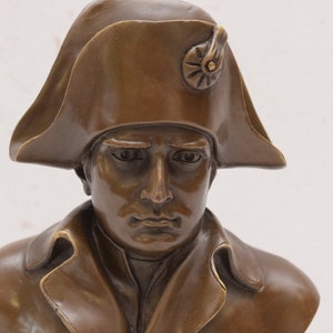 May include: Bronze bust sculpture of a man wearing a bicorne hat. The sculpture is detailed and realistic, capturing the man's facial features and the texture of his clothing.