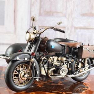 May include: A vintage-style motorcycle with a sidecar, crafted from metal. The motorcycle features a black and brown color scheme with gold accents on the wheels and engine. The sidecar is attached to the left side of the motorcycle.