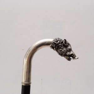 Op de afbeelding: Een zilveren wandelstok met een gedetailleerd everzwijnkop-handvat.