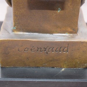 May include: Bronze sculpture of a seated figure with a signature on the base that reads "Coenraed".