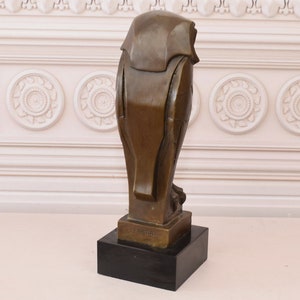 May include: A bronze sculpture of an owl with a geometric design. The owl is standing on a black base. The sculpture is signed "E. Barye" on the base.