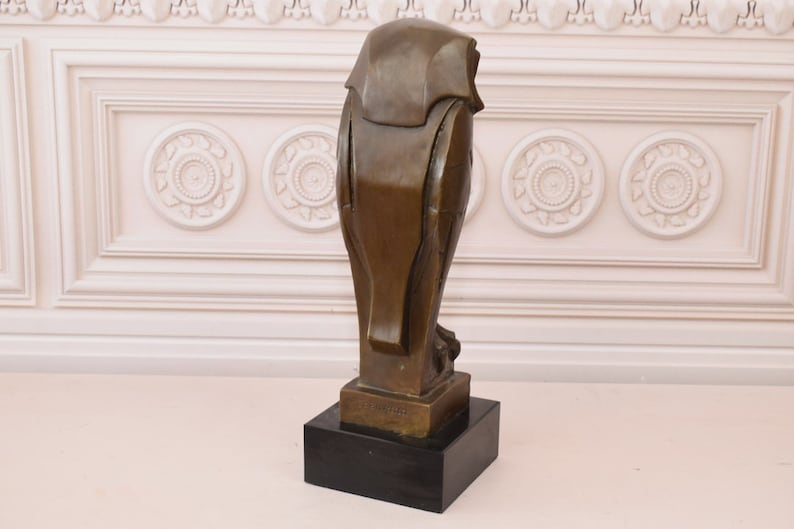 May include: A bronze sculpture of an owl with a geometric design. The owl is standing on a black base. The sculpture is signed "E. Barye" on the base.