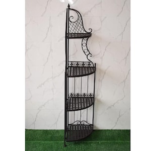 Puede incluir: Estantería esquinera de hierro forjado negro con cuatro estantes semicirculares. Los estantes tienen un patrón tejido, y el marco presenta adornos decorativos y un diseño de celosía en la parte superior. La estantería está diseñada para colocarse contra una pared.
