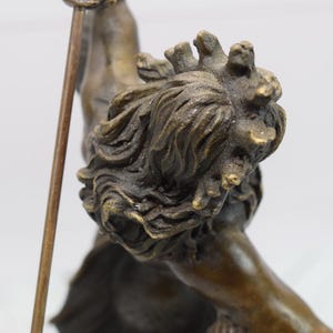 Puede incluir: Escultura de bronce de una figura mitol&oacute;gica con una lanza. La figura tiene una melena de le&oacute;n detallada y est&aacute; en una pose din&aacute;mica. La escultura es de color bronce antiguo c&aacute;lido.
