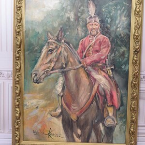 K&ouml;nnte beinhalten: Ein gerahmtes &Ouml;lgem&auml;lde eines Mannes auf einem Pferd. Der Mann tr&auml;gt eine rot-goldene Uniform und einen Federhut. Das Pferd ist braun und hat ein wei&szlig;es Zaumzeug. Das Gem&auml;lde ist unten rechts mit "Wojciech Kossak" signiert.