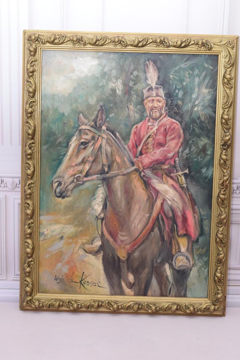 K&ouml;nnte beinhalten: Ein gerahmtes &Ouml;lgem&auml;lde eines Mannes auf einem Pferd. Der Mann tr&auml;gt eine rot-goldene Uniform und einen Federhut. Das Pferd ist braun und hat ein wei&szlig;es Zaumzeug. Das Gem&auml;lde ist unten rechts mit "Wojciech Kossak" signiert.