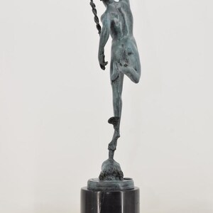 May include: A bronze sculpture of a figure in motion, poised on one leg atop a pedestal. The figure is reaching upwards with one arm, and has a winged helmet. The sculpture is mounted on a black marble base.