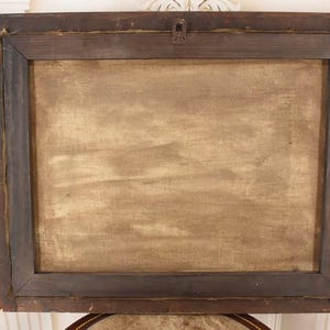 Pu&ograve; includere: Retro di un dipinto incorniciato. La cornice in legno marrone scuro racchiude una tela con una superficie strutturata marrone chiaro. Un gancio di metallo &egrave; fissato nella parte superiore centrale della cornice.