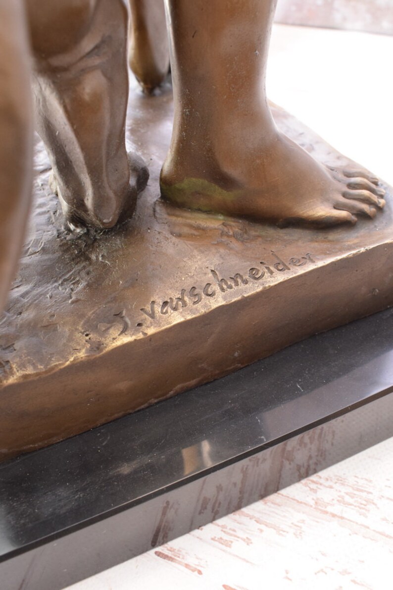 May include: Bronze sculpture of two figures standing on a rectangular base. The base is inscribed with the artist's signature, "J. Varschneider".