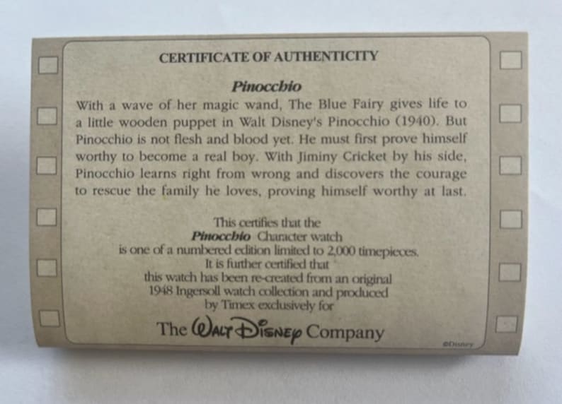 May include: A certificate of authenticity for a limited edition Pinocchio character watch. The certificate is printed on brown paper with a wood grain texture. The text states that the watch is one of 2,000 timepieces and was re-created from an original 1948 Ingersoll watch collection. The certificate is signed by The Walt Disney Company.