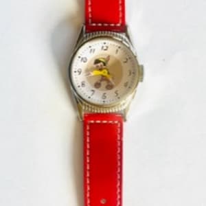 May include: A red leather wristwatch with a white face and black numbers. The watch face features a cartoon character with a yellow hat.
