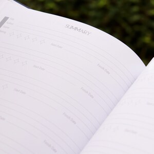 May include: A white book with a black cover and the word "SUMMARY" printed on the top of the page. The book has a section for recording book titles, authors, genres, and ratings.