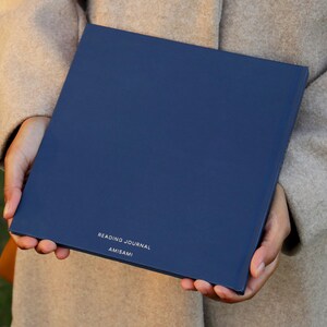 May include: A navy blue reading journal with the text "READING JOURNAL" and "AMISAMI" printed in white on the front cover.