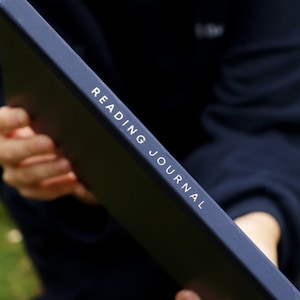 May include: A black reading journal with the words "READING JOURNAL" printed in white on the spine.
