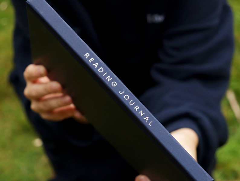 May include: A black reading journal with the words "READING JOURNAL" printed in white on the spine.