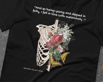 May include: Black t-shirt featuring a floral and skeletal design. The text "And so being young and dipped in folly, I fell in love with melancholy." is printed on the shirt. The text "EDGAR ALLAN POE" is printed below the design.