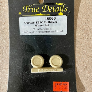 May include: A plastic model kit of two main wheels for a Curtiss SB2C Helldiver aircraft. The kit is labelled "True Details" and "48066". The wheels are beige and have a black background. The kit is priced at £3.50.
