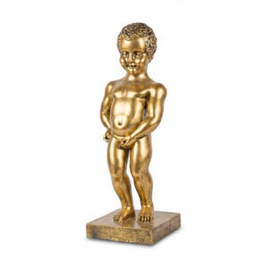 Könnte beinhalten: Eine goldfarbene Statue eines kleinen Jungen, der auf einem quadratischen Sockel steht. Die Statue ist eine detaillierte Darstellung eines Kindes mit glatter, reflektierender Oberfläche. Der Junge ist in einer klassischen Pose dargestellt.