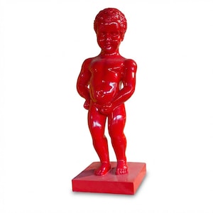May include: A glossy red statue of a young child standing on a square base. The child is depicted with a slightly chubby physique and is holding their genitals. The statue has a smooth, reflective surface and is set against a white background.