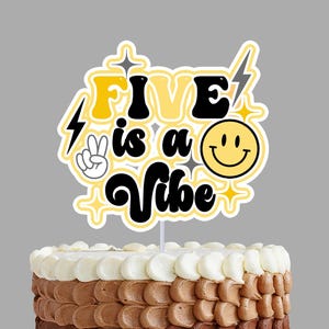 Puede incluir: Un pastel en capas con glaseado blanco, marrón claro y marrón oscuro. Un adorno para pastel que dice "FIVE is a Vibe" con un signo de la paz, una carita sonriente y rayos. El pastel está sobre un soporte blanco.