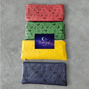 May include: Four zippered pouches with different colored backgrounds and a black and white Harry Potter themed print. The pouches are stacked on top of each other. The colors are red, green, yellow, and blue.