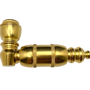 May include: A gold-colored metal pipe with a rounded bowl and a long, cylindrical stem. The pipe has a decorative design on the stem.