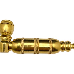 May include: A gold metal pipe with a rounded bowl and a long, cylindrical body. The body has a decorative pattern of ridges and grooves.