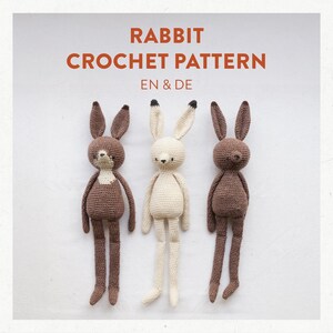 Könnte beinhalten: Drei gehäkelte Hasenspielzeuge, eines braun, eines weiß und eines braun mit einer weißen Brust. Die Spielzeuge sind in einer Reihe auf weißem Hintergrund angeordnet. Der Text "RABBIT CROCHET PATTERN EN & DE" ist über den Spielzeugen angezeigt.