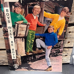May include: Vintage magazine cover featuring four boys in colorful sweaters. The cover reads "Spinnerin" and "Boys Will Be Boys." The boys are posed on a train car, wearing green, orange, yellow, and blue sweaters. The magazine is Volume 189.